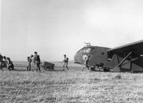 Airborne personnel moving off with trolleys after unloading a WACO Glider. June 1943.