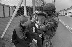 Paratrooper applies camouflage cream to teenage boys in Cookstown