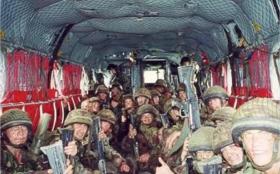 Colour photo of paras in camo looking to the camera inside a chinook helicopter