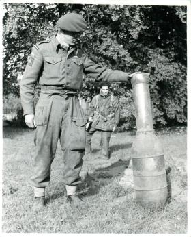 Airborne Signaller holds unexploded German rocket in Hartenstein Hotel grounds, September 1944.
