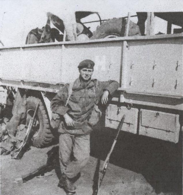 Sapper Brian Guest in Denison smock leaning on truck