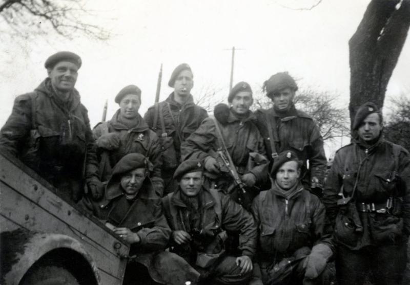 OS John kneeling with large glove on his hand as he suffered frostbite in the Ardennes