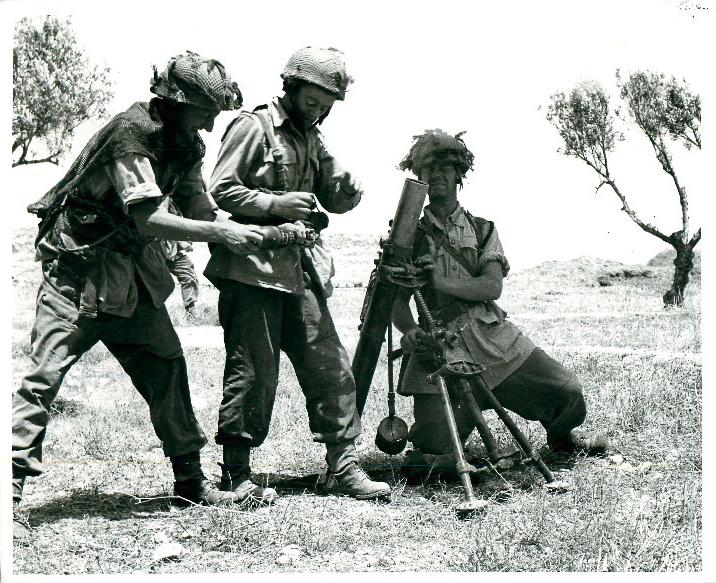 Three men from a 3-inch mortar team loading ammunition, North Africa, 1943